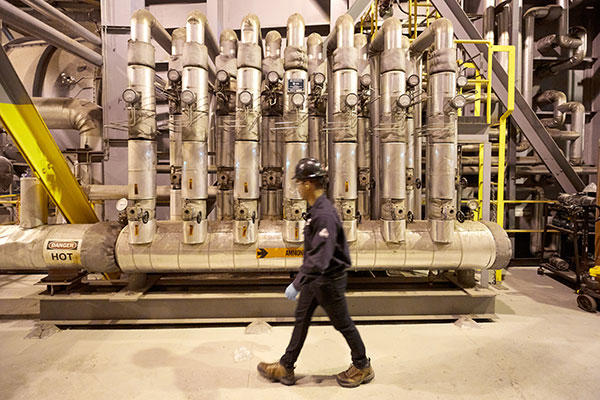 Employé du personnel marchant à l'intérieur d'un site industriel de production d'énergie